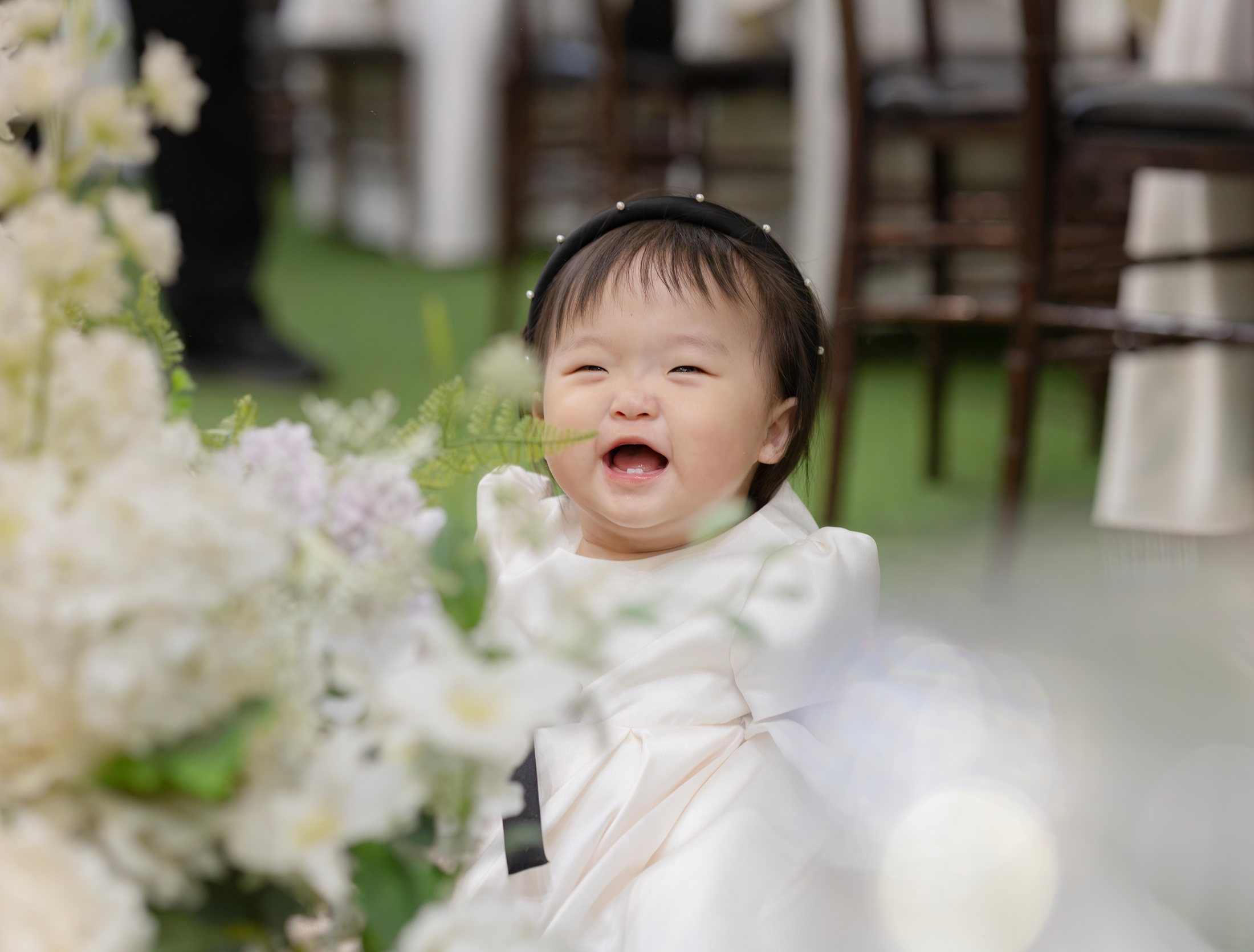 꽃 사이에서 환하게 웃는 돌잔치 주인공 아이